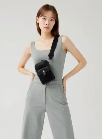 Standing with hands on hips, crossbody bag